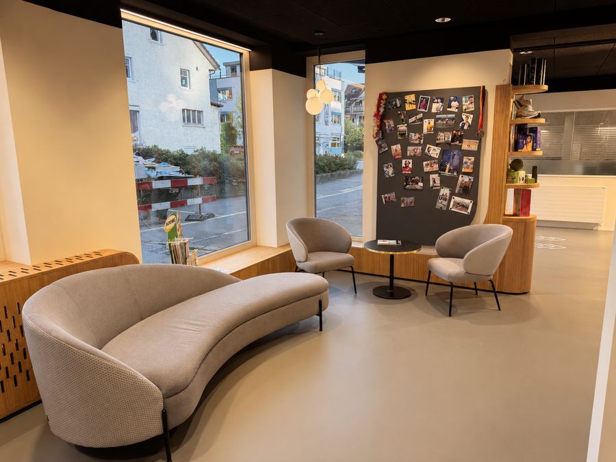 Lounge mit geschwungenem Sofa und Sportler-Wand am Fenster